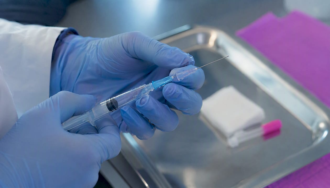 Hands inspecting syringe and needle hub connection