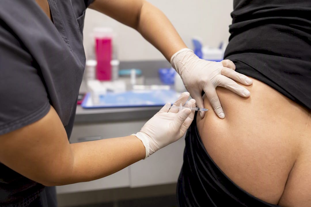 Hands administering intramuscular injection at ventrogluteal site