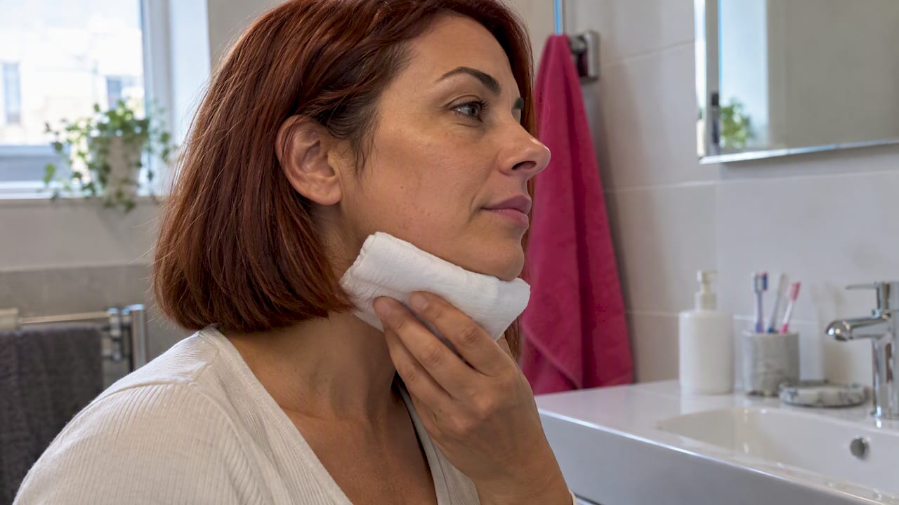 Wrapped cold compress held gently beneath jaw